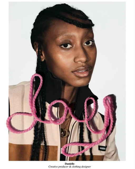 Portrait of an African-American woman with dark braided hair, wearing a jacket with a tan and brown pattern, against a white background.
