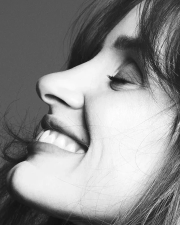 Monochrome close-up profile portrait of a smiling woman with bangs by photographer Ben Hassett