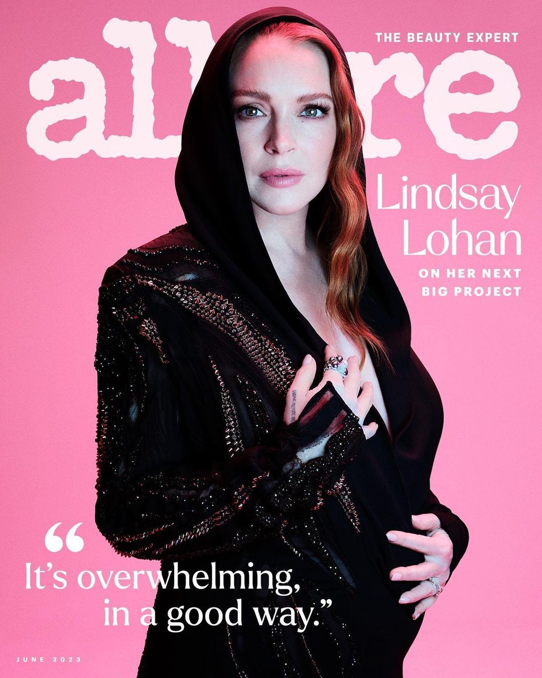 Allure magazine cover featuring Lindsay Lohan in a black hooded garment on a pink background, promoting her upcoming project in June 2023.