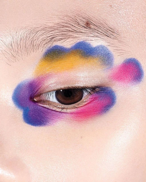 Eye makeup fashion shot. Portrait of fair-skinned adult woman with dramatic pink, blue and yellow eye shadow design.