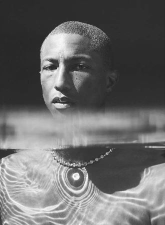 Monochrome portrait of adult male partially submerged in water with jewelry, the water reflecting light patterns on his body.