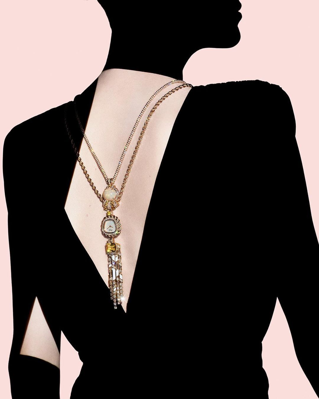 Back view of a person wearing a black dress and an ornate gold necklace with crystals on a light pink background, fashion photography.