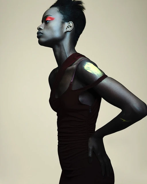 Elegant portrait of a Black woman in a burgundy dress with makeup, facing left against a neutral backdrop in a studio setting.