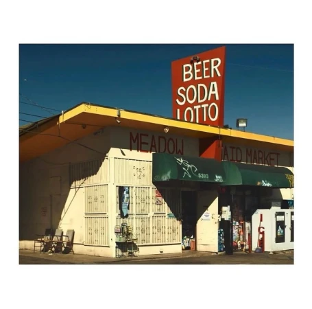 Exterior view of Meadow Maid Market under a blue sky, featuring a prominent 'Beer Soda Lotto' sign and an awning-covered entrance.