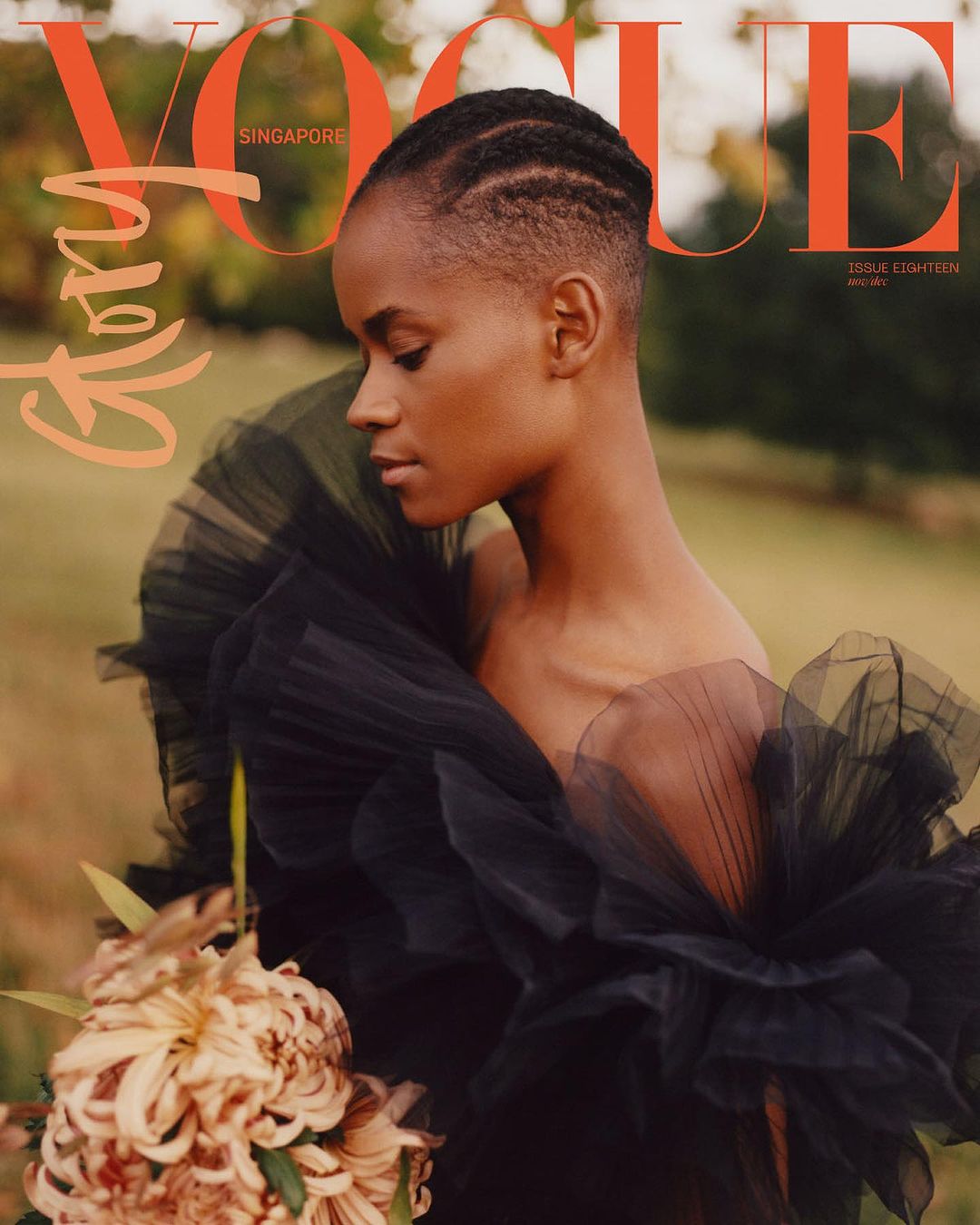 Magazine cover featuring a portrait of a woman wearing a black tulle dress, holding flowers, with the Vogue Singapore logo at the top.
