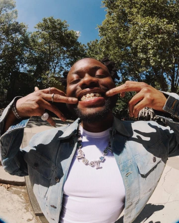 Black man smiling and pulling his cheeks back to show grillz in a fisheye portrait by Ben Rayner.