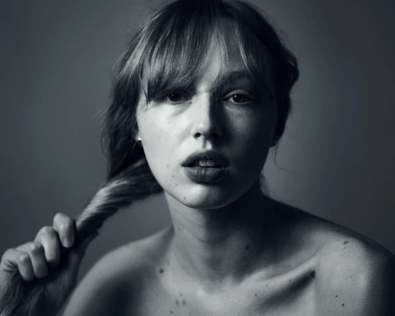 Monochrome portrait of a young woman with bangs holding her hair by photographer Kasey Priest