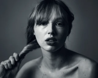 Monochrome portrait of a young woman with bangs holding her hair by photographer Kasey Priest