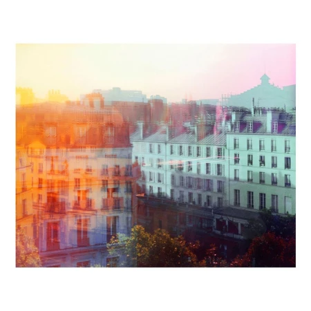 Cityscape view with multiple buildings in Paris, France, featuring residential buildings, rooftops, and trees against a soft, colorful sky.