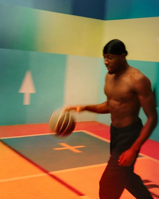 African American man dribbles a basketball on an indoor court with colorful walls and floor markings, action shot, active lifestyle.