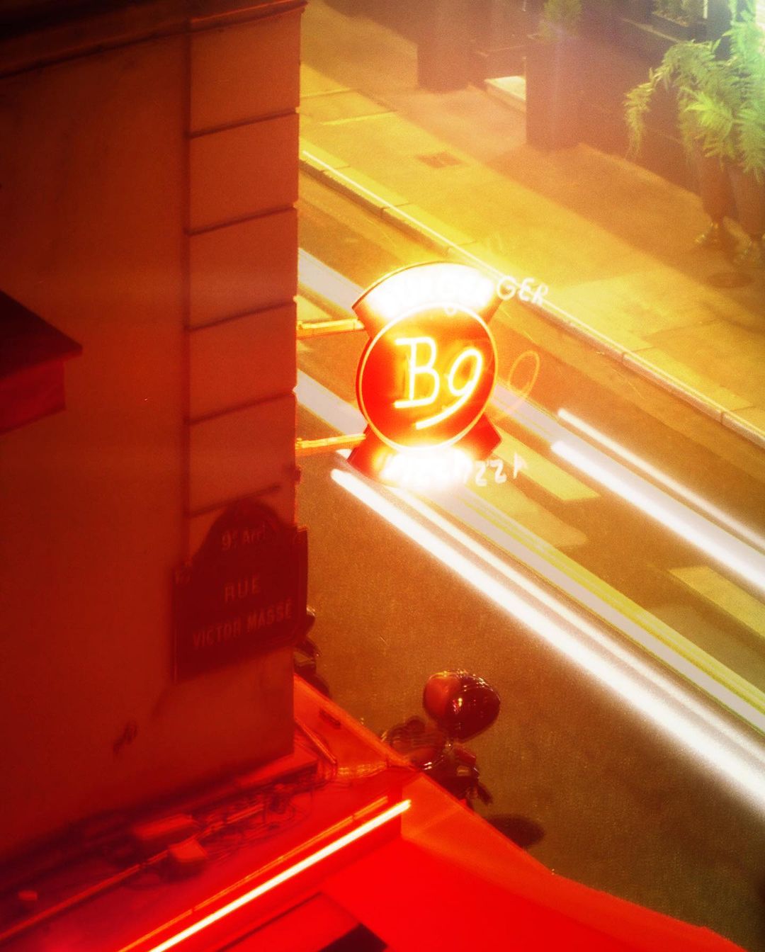 Illuminated neon restaurant sign glows brightly on a city street at night with long exposure light trails, creating a vibrant urban scene.