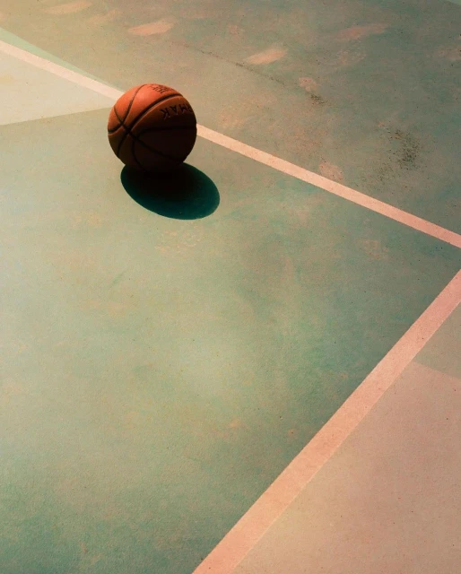 A basketball rests on a green and white court, creating a simple yet striking image focused on sport and recreation.