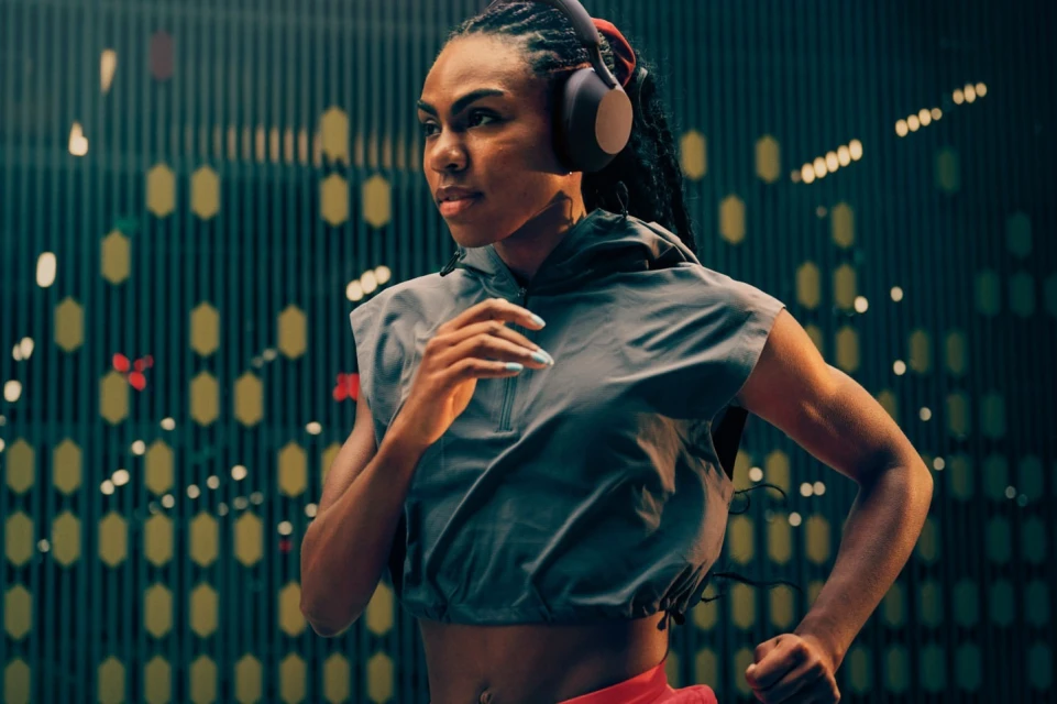 Athletic woman with braids jogging with headphones on in an urban environment with a patterned background. Fitness lifestyle shot.