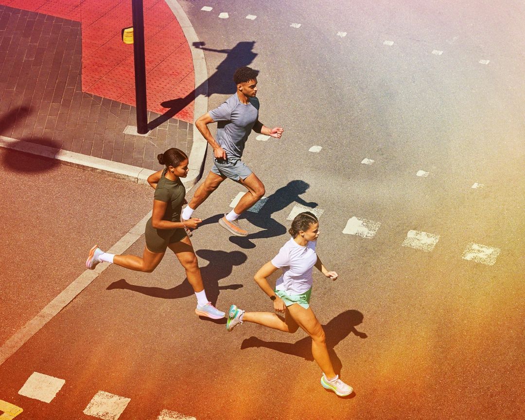 High-angle view of three athletic adults running on a city street on a sunny day, promoting a healthy and active lifestyle.