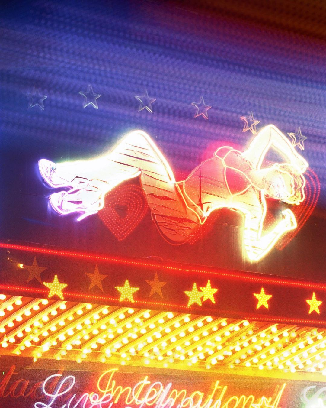 Neon sign featuring a reclining figure of a woman with stars on a blue background, with the text 'International' visible at the bottom.