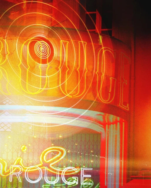 Neon sign of the Moulin Rouge in Paris with geometric light effects, orange and red colors, and architectural details.