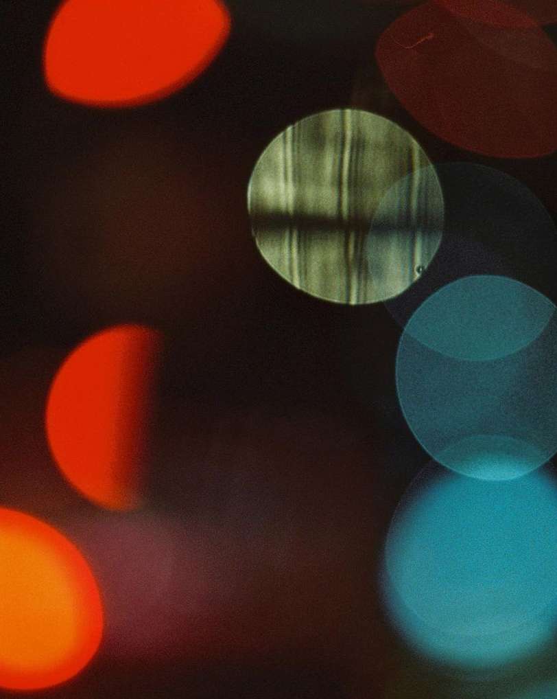 Abstract blurred background featuring vibrant circles of light in red, teal, and yellow with a dark and hazy atmosphere.