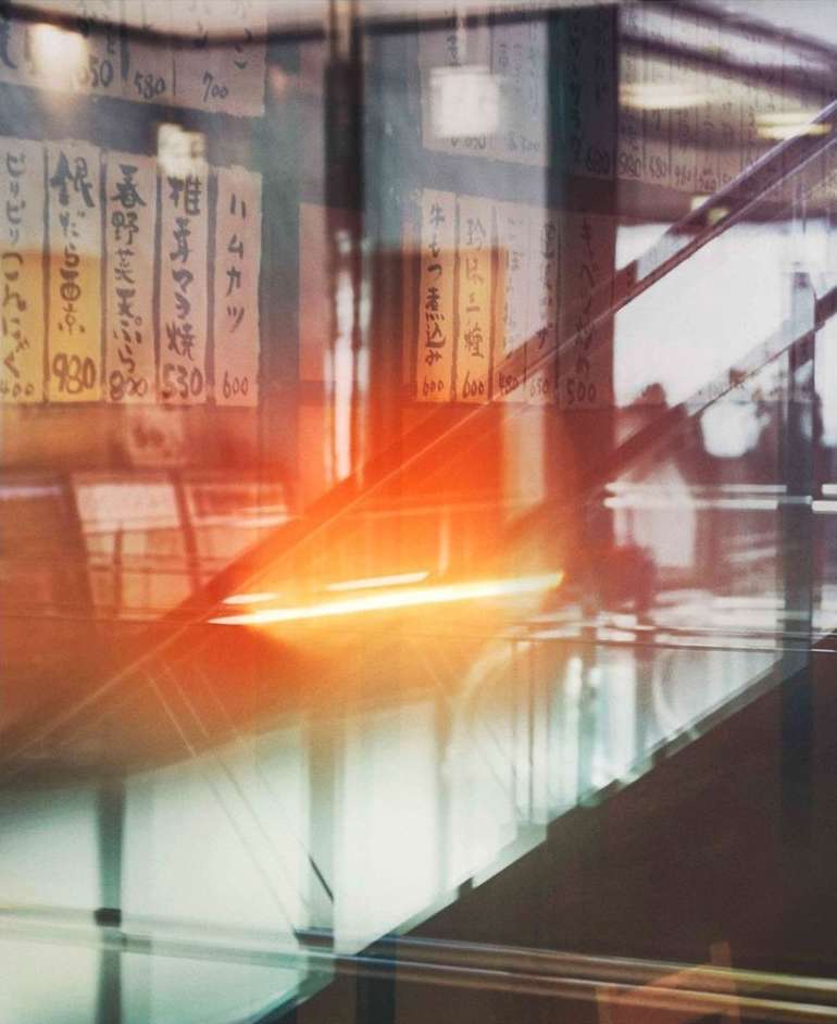 Abstract view of escalators with a menu board and bright light flare creating an artistic, unique, and modern visual composition.