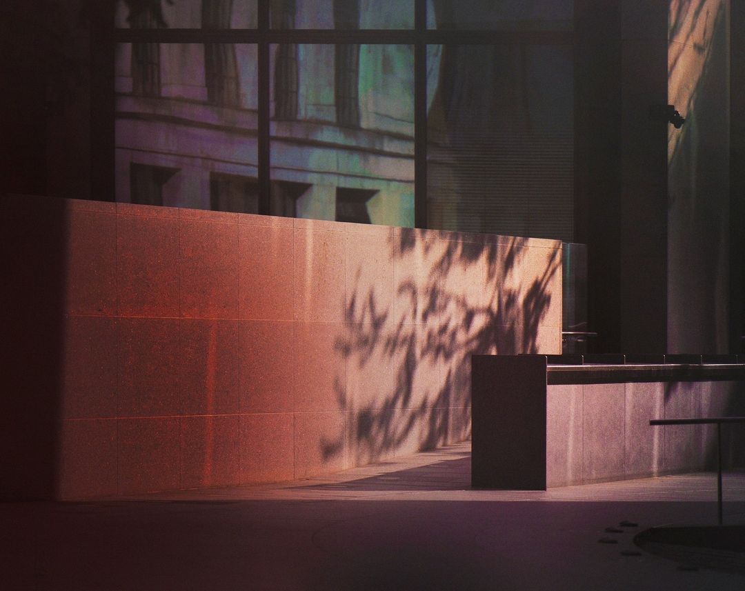 Contemporary interior featuring a textured wall with shadow patterns, and a sleek, minimalist design in a dimly lit urban setting.