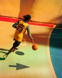 Basketball player dribbling a ball on an outdoor court, captured from a high-angle view by photographer Ben Stockley.