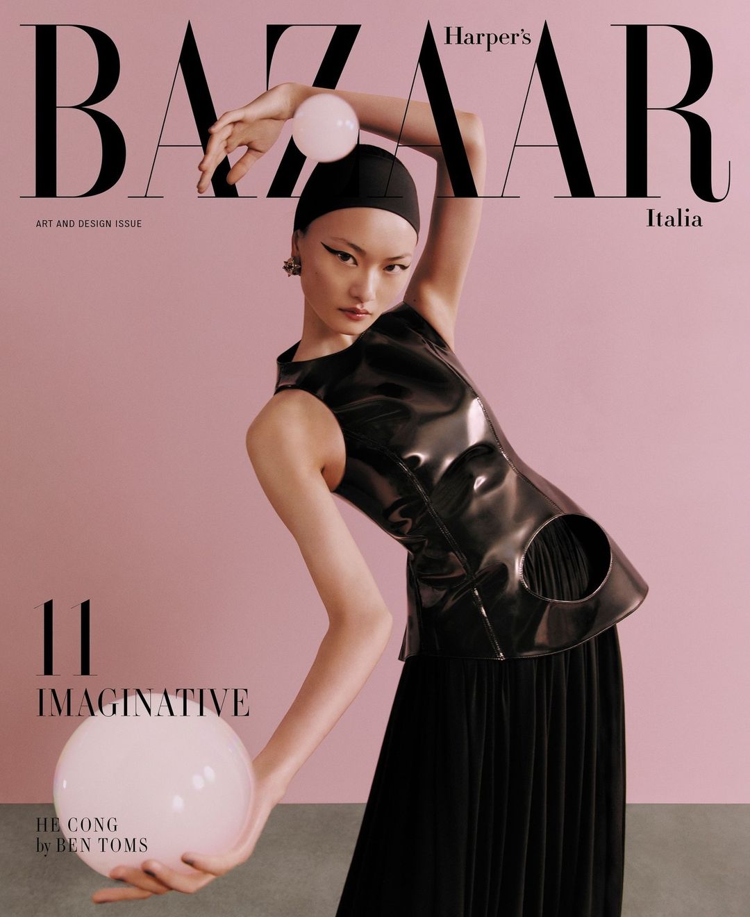 Magazine cover featuring an Asian female model in a black outfit holding two large white spheres against a pale pink background.