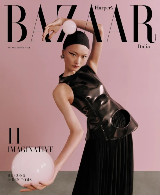 Magazine cover featuring an Asian female model in a black outfit holding two large white spheres against a pale pink background.