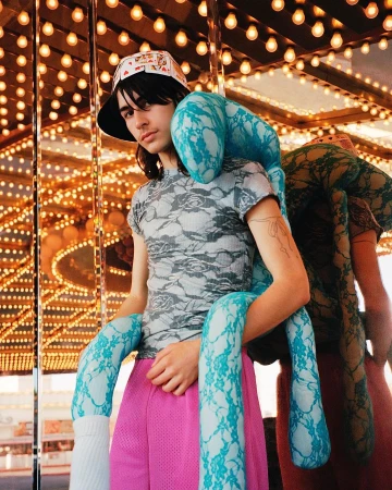 Young adult with unique plush toy, posing in a bright carnival-style setting with eye-level angle. Casual fashion, quirky and fun aesthetic.