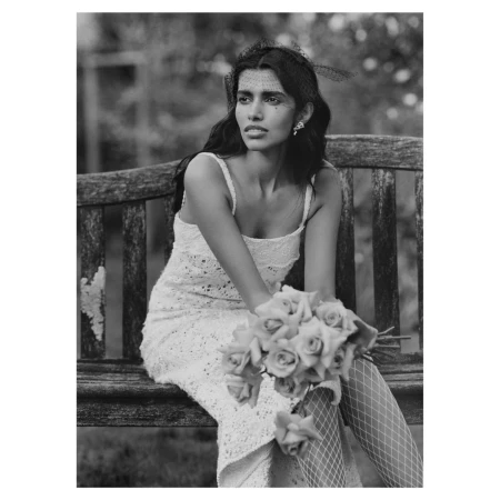 Black and white portrait of a woman in a lace dress holding roses on a wooden bench