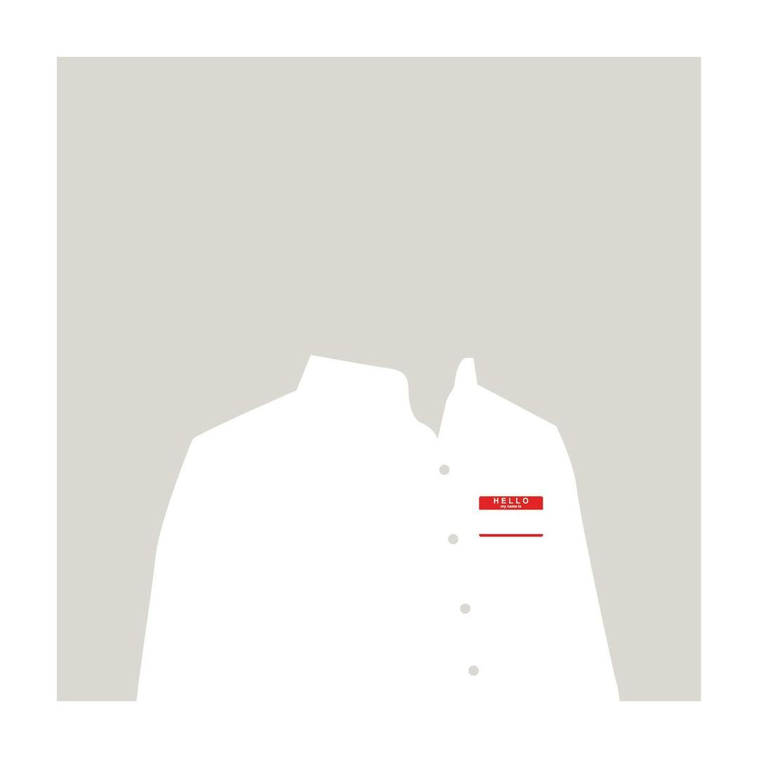 Illustration of a white collared shirt with a red name tag on a light gray background. The focus is on the shirt and the nametag.
