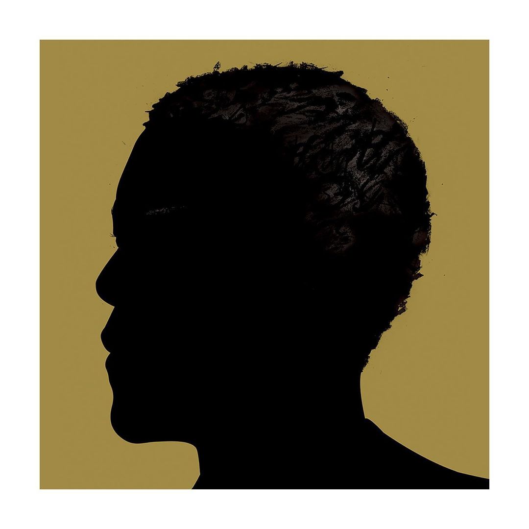 Silhouette portrait of an adult male with short hair in black against a gold background, creating a striking, artistic contrast.