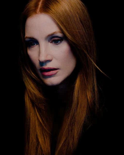 Portrait of a red-haired woman with a solemn expression against a dark background, showcasing her makeup and flowing hair.