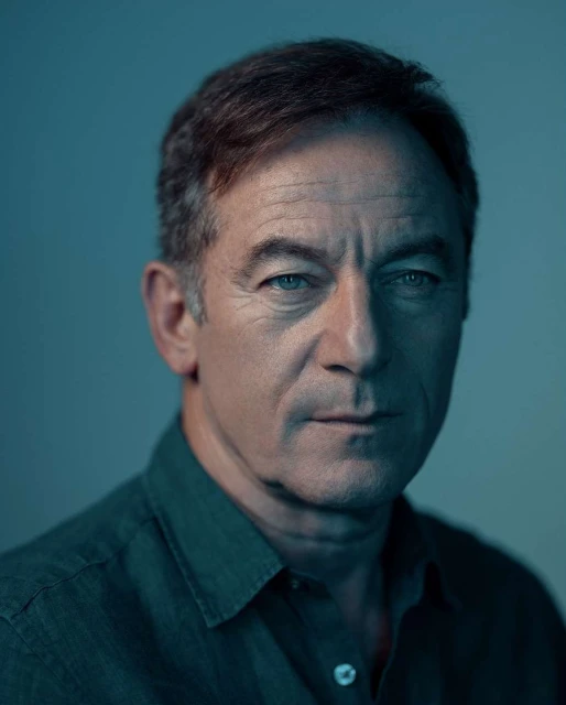 Portrait of a middle-aged man with short brown hair in a dark teal button-up shirt against a soft blue gradient background in a photo studio.