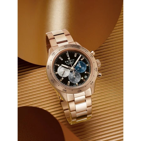 Rose gold Zenith watch with black dial and chronograph function on a shiny gold background, product shot for luxury timepieces.
