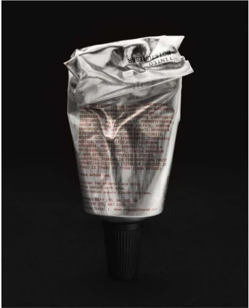 Silver tube of tinted moisturizer with black cap. Close-up product shot on dark background emphasizing the texture and packaging.