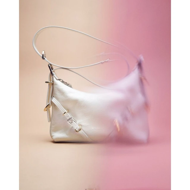 Elegant white leather handbag with a slender strap, artfully displayed against a gradient pink and beige background.