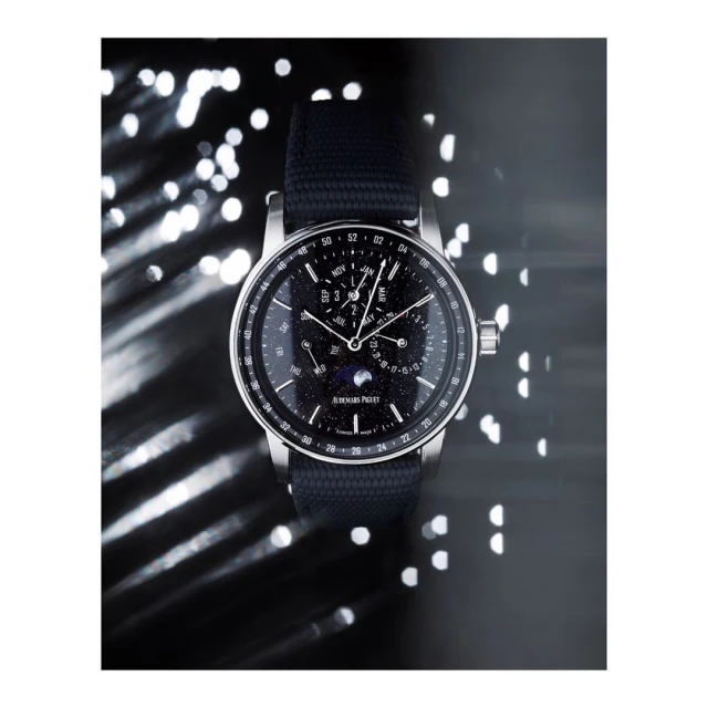 Luxury wristwatch with a dark band and black dial, highlighted by a silver casing and hands, set against a bokeh background.