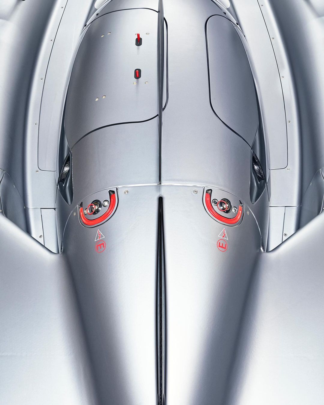 Overhead shot of a silver race car displaying sleek aerodynamic design, red circular accents, and streamlined bodywork.