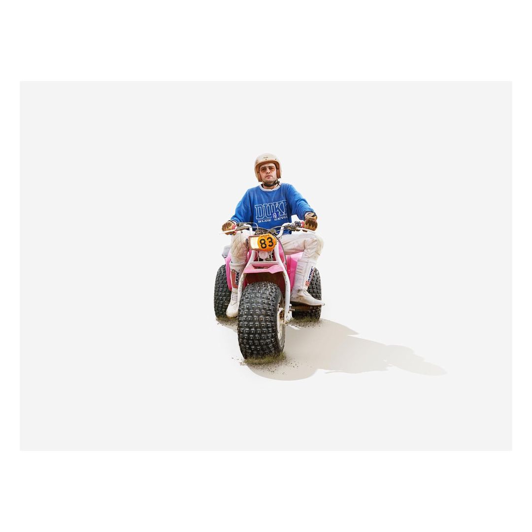 An adult rides a pink three-wheeled ATV on a bright white background, creating a minimalist image focused on transportation and recreation.