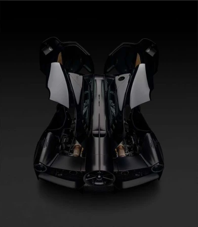 Sleek black car on a black surface shown in a studio shot from the front with its doors open for an interesting automobile product shot.