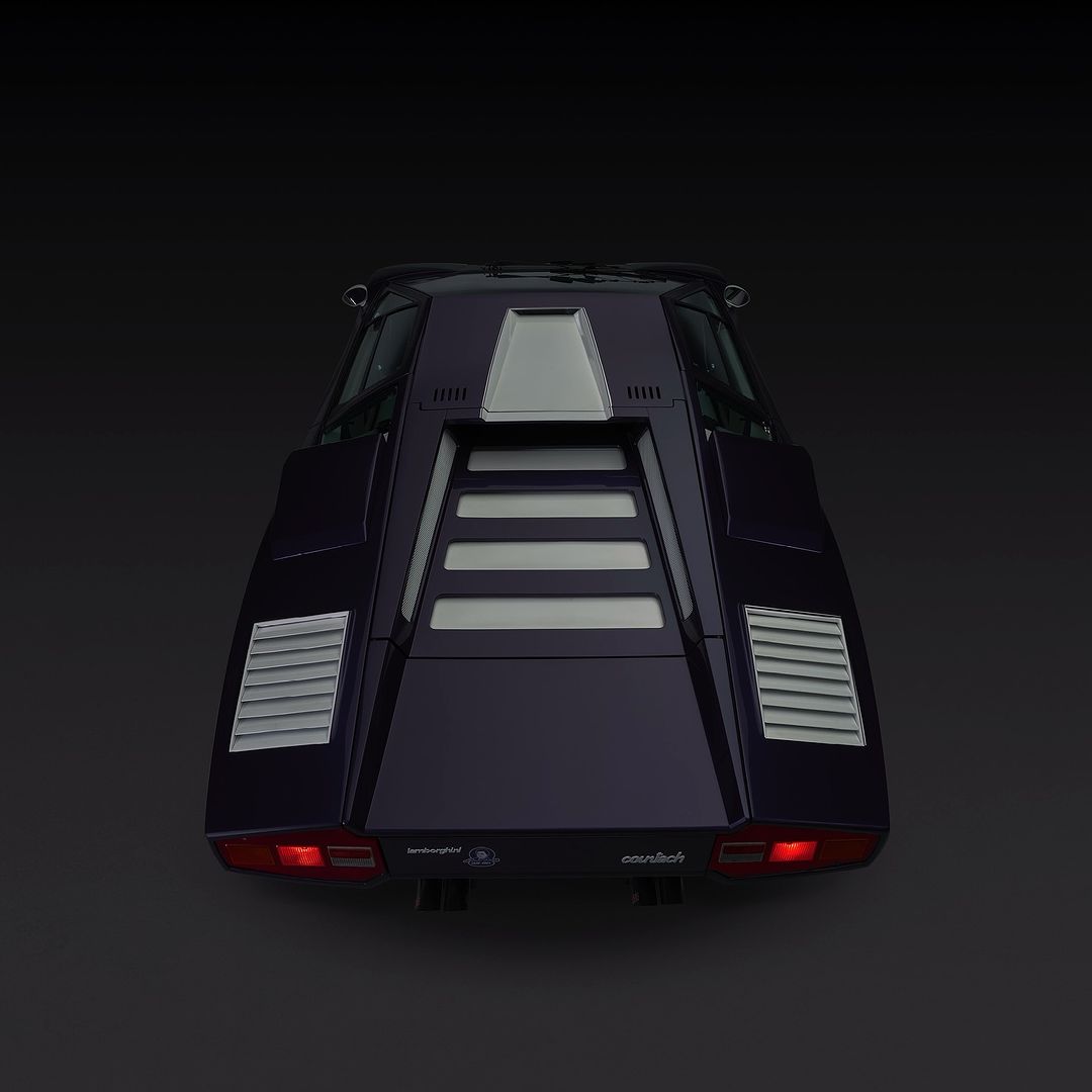 Rear view of a purple Lamborghini Countach with silver trim against a dark background, highlighting its angular design and taillights.