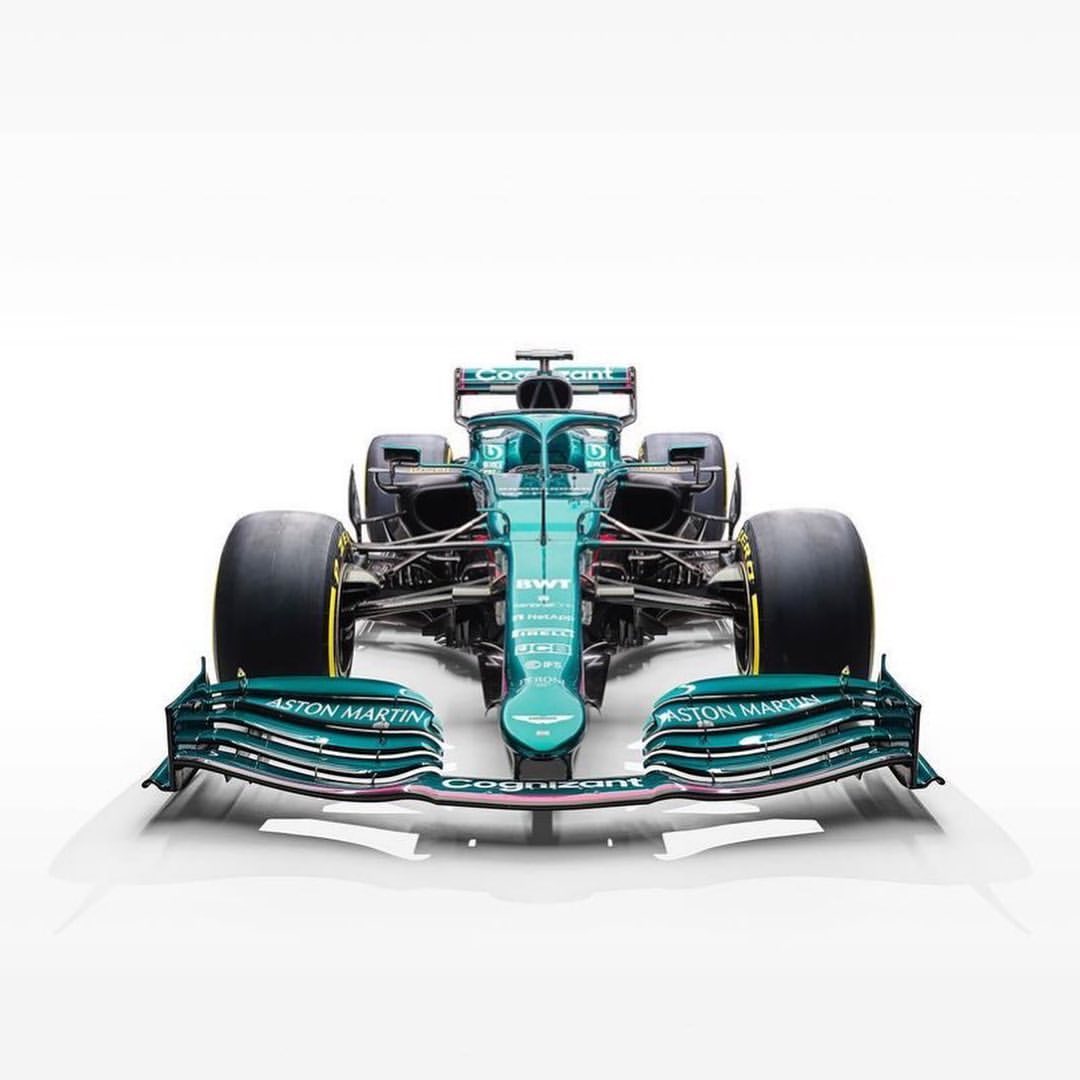 Front view of a green Aston Martin Formula 1 race car against a white background, showcasing its aerodynamic design and racing tires.
