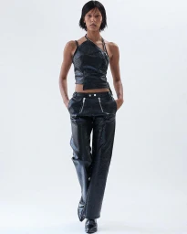 Model in black textured halter top and matching trousers posing against a plain white studio background.