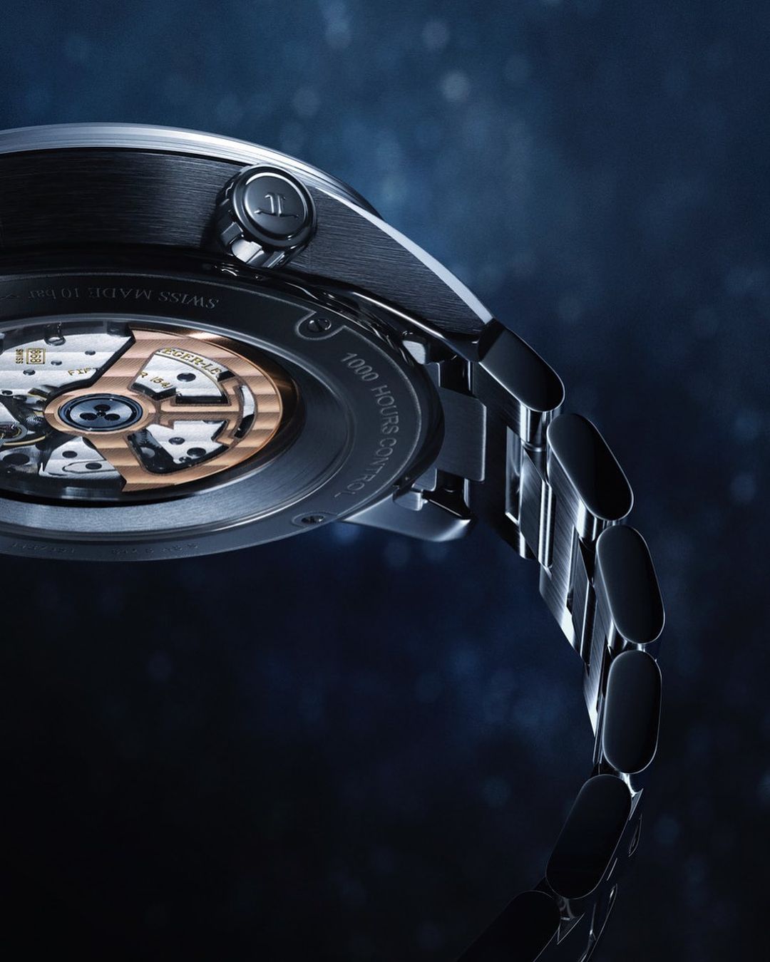 Close-up of a wristwatch with an open case back showcasing the intricate inner workings and gears against a dark, speckled backdrop.