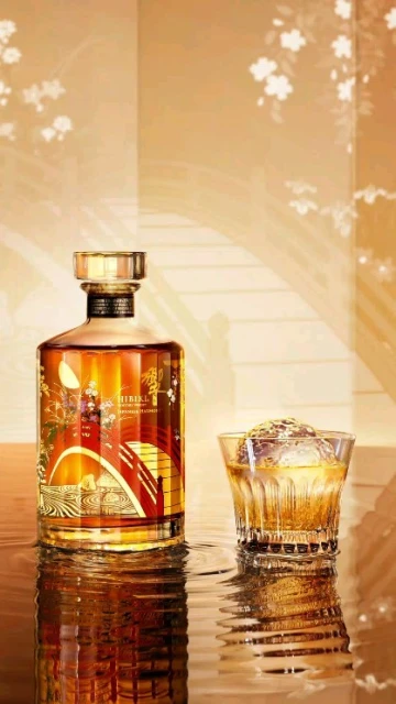Still life shot of a decorated whiskey bottle and a glass of whiskey with an ice ball, on a wet reflective surface.
