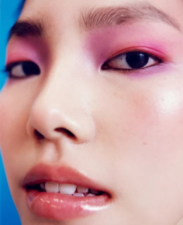 Extreme close-up portrait of an Asian woman featuring vibrant pink eyeshadow and glossy lips photographed by Benjamin Madgwick.