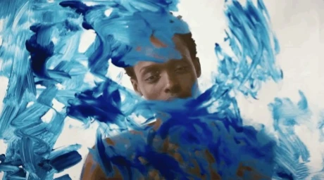 Portrait of a Black man behind a glass surface smeared with expressive blue paint strokes.
