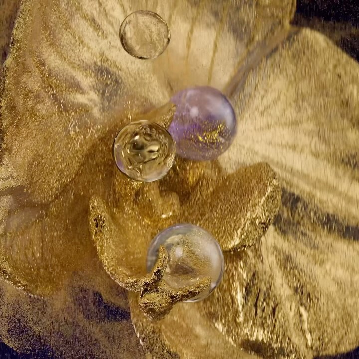 A textured gold surface with shimmering clear and purple orbs creates an abstract, opulent scene.