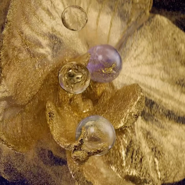 A textured gold surface with shimmering clear and purple orbs creates an abstract, opulent scene.