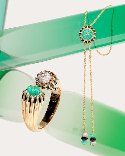 Luxurious gold ring and necklace featuring green and white gemstones set against a light backdrop with a translucent green accent.