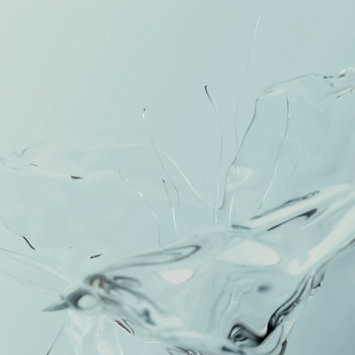 Abstract close-up of transparent liquid in motion, creating a dynamic splash against a pale background, artistic and clean look.